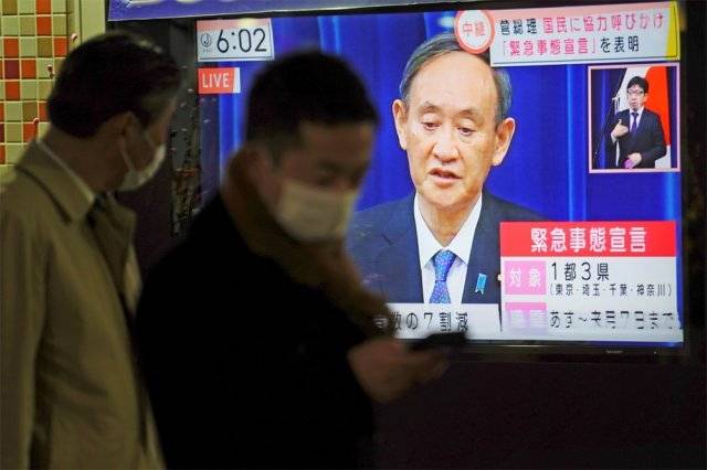 7일 스가 요시히데 일본 총리가 도쿄 등 수도권 4개 지역에 코로나19 방역을 위한 긴급사태 선언을 발표하고 있는 가운데 마스크를 쓴 시민들이 생중계 화면을 지켜보고 있다. 도쿄=AP 뉴시스