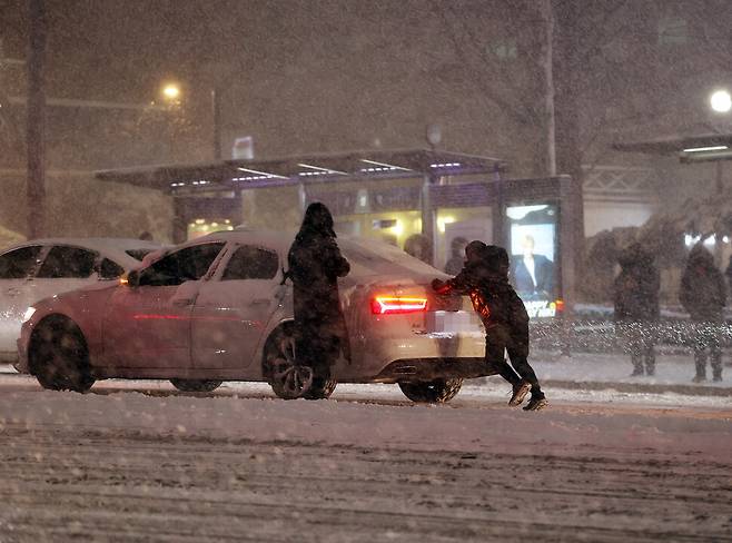 대설주의보 내려진 지난 6일 저녁 서울 삼성역 인근 도로에서 시민들이 수입차를 밀고 있다. 연합뉴스