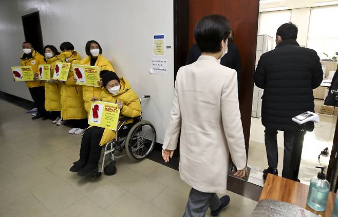 Democratic Party of Korea lawmaker Back Hye-ryun, chairperson of the first legislation review subcommittee at the parliamentary Legislation and Judiciary Committee enters the meeting room after walking past the Justice Party lawmakers holding signs calling for the lawmakers to enact a bill on the punishment of corporations for serious industrial hazards on January 6. National Assembly press photographers