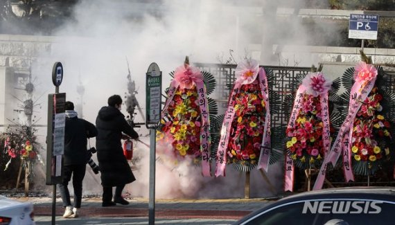 대검찰청 관계자들이 5일 오전 서울 서초구 대검찰청 앞에서 한 남성이 분신시도를 하며 화환에 불을 붙이자 소화기로 진화하고 있다.