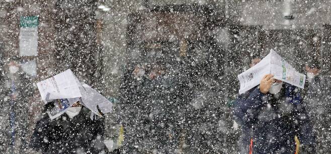 눈이 내리고 있는 12일 오후 서울 중구 하나은행 앞에서 시민들이 신문지로 눈을 막으며 이동하고 있다. /뉴시스