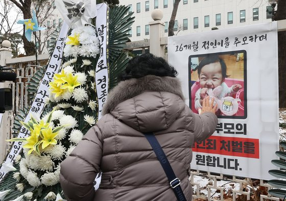 11일 오전 서울 양천구 남부지방검찰청 앞에 설치된 정인이 사진을 한 시민이 어루만지고 있다. 이날 대한아동학대방지협회는 정인이 양부모 재판을 앞두고 엄벌을 촉구하며 근조화환과 바람개비를 설치했다. 연합뉴스