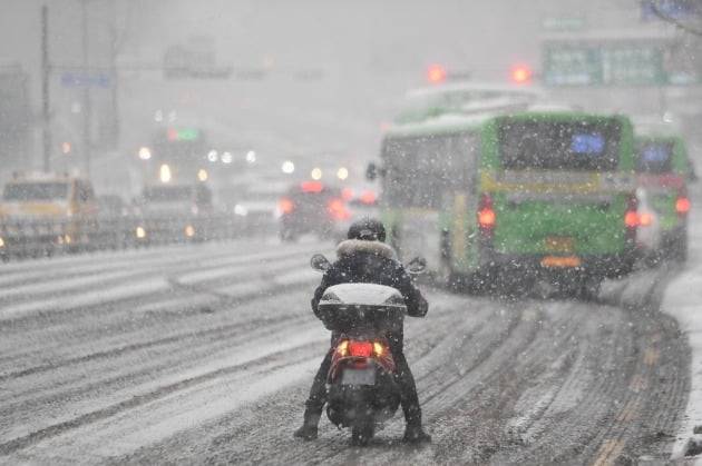 갑작스런 폭설이 내린 12일 오후 서울 방이동 일대에서 배달음식 라이더가 운행을 멈추고 생각에 잠겨 있다. [사진=최혁 한경닷컴 기자]