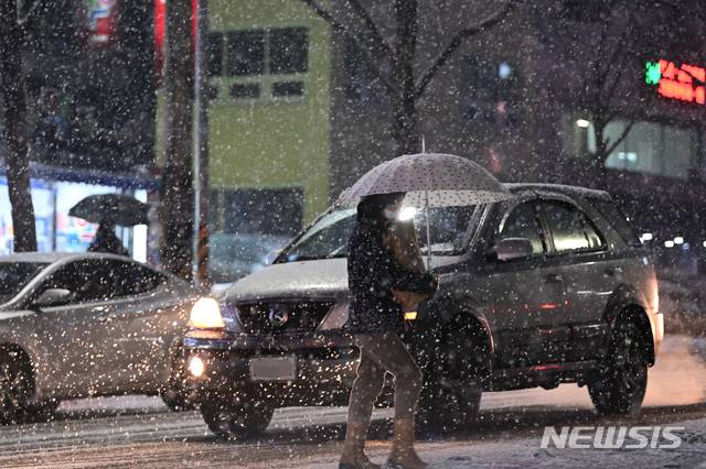 [수원=뉴시스]김종택 기자 = 수도권 일부지역에 대설주의보가 발효된 12일 오후 경기 수원시 팔달구 인계동에서 시민이 눈을 맞으며 걸어가고 있다. 2021.01.12. jtk@newsis.com