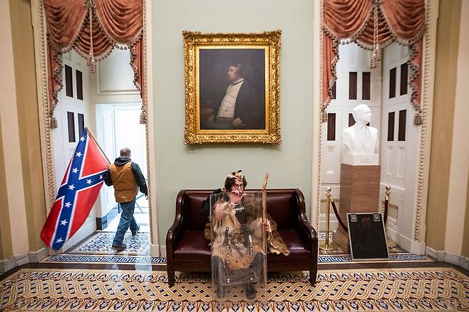 ⓒEPA의사당을 점거한 한 트럼프 지지자가 남부연합기(the Confederate Battle Flag)를 들고 이동하고 있다.