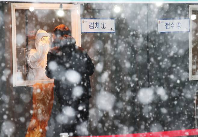 눈이 내린 12일 오후 서울역 광장에 마련된 코로나19 임시 선별검사소에서 시민들이 검사를 받고 있다. 연합뉴스