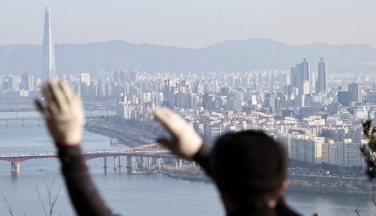 한 시민이 서울 매봉산에서 송파구, 강남구 일대 아파트 밀집 지역을 바라보고 있다. <연합뉴스>