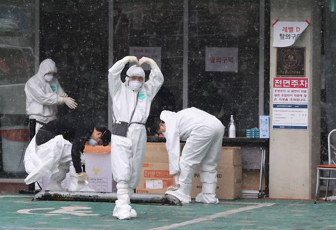 지난달 29일 코로나19 확진자 발생으로 코호트 격리된 서울 구로구의 한 요양병원에서 병원 관계자들이 병원내 환자를 돌본 후 환복하며 취재진에게 인사하고 있다. (사진=연합뉴스)