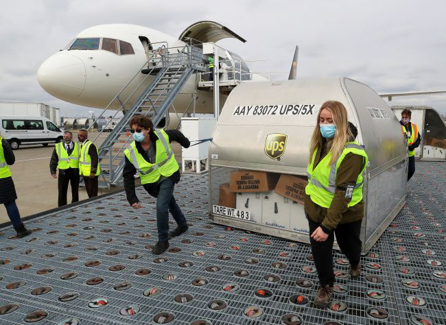 미국 택배회사 UPS 노동자가 13일(현지시간) 켄터키주 루이빌의 무하마드 알리 국제공항에서 미국 화이자·독일 바이오엔테크의 코로나19 백신이 담긴 컨테이너를 옮기고 있다. 로이터연합뉴스