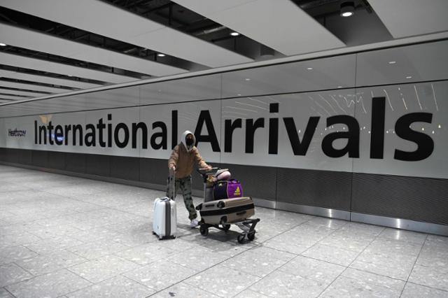 영국 런던 히드로공항에 이달 15일 마스크를 착용한 한 입국자가 짐을 끌고 가고 있다. 런던=AFP 연합뉴스
