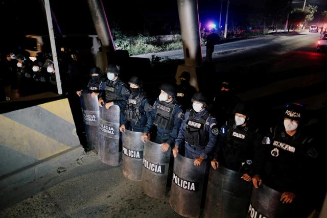 조 바이든 미국 대통령 당선인의 취임식을 앞두고 중남미 이민자 행렬이 시작된 가운데 13일 산페드로 술라에서 온두라스 경찰들이 이민자행렬의 이동로를 차단한 채 서 있다. 산페드로술라=로이터 연합뉴스