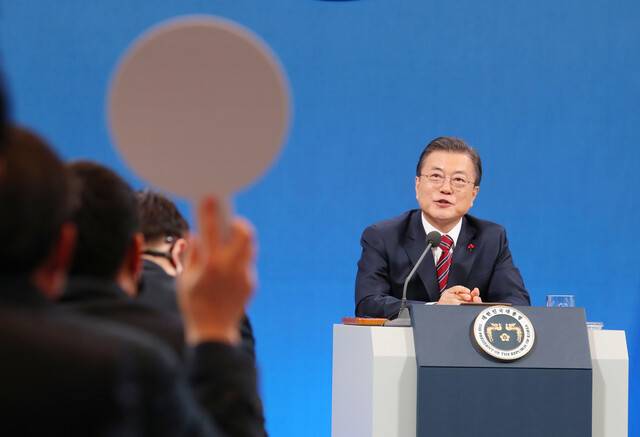 문재인 대통령이 18일 청와대 춘추관에서 열린 온·오프 혼합 방식의 신년 기자회견에서 현안 질문을 하기 위해 번호판을 든 기자들을 바라보고 있다. 청와대사진기자단