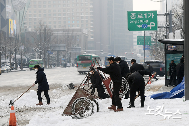 서울 광화문광장 인근에서 관계자들이 쌓인 눈을 치우고 있다. 이한형 기자