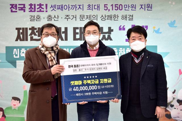 최근 셋째 딸을 얻은 박 모(가운데) 씨가 충북 제천시로부터 주택자금 지원금과 기념 선물을 받은 후 이상천(왼쪽) 제천시장과 기념 촬영을 하고 있다. /사진 제공=제천시