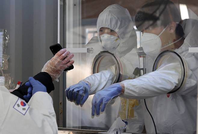 19일 오전 서울 용산구 용산역광장에 설치된 임시 선별진료소에서 의료진이 한 외국인이 보여주는 메시지를 읽고 있다. 중앙방역대책본부에 따르면 이날 0시 기준으로 신규 확진자는 386명으로 집계됐다.  2021.1.19 연합뉴스