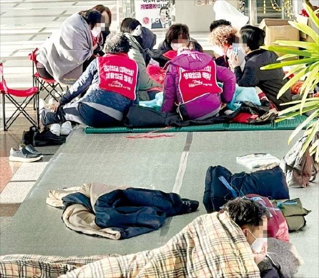 < 방역지침도 무시한채… > 전직 LG트윈타워 청소근로자들이 지난달부터 서울 여의도 LG트윈타워 1층 로비를 점거한 채 농성을 이어가고 있다. 이들은 LG 측의 계약해지로 일자리를 잃었다며 70세까지 이곳에서 근무할 수 있도록 해달라고 요구하고 있다.  독자 제공