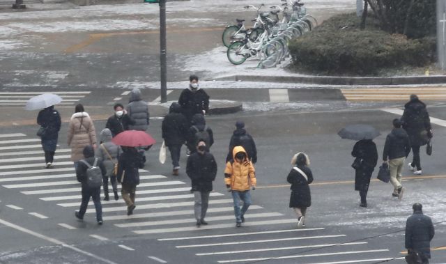 중부지방 중심으로 눈이 내린 지난 18일 오전 서울 광화문사거리에서 시민들이 우산을 쓰고 횡단보도를 건너고 있다. 연합뉴스