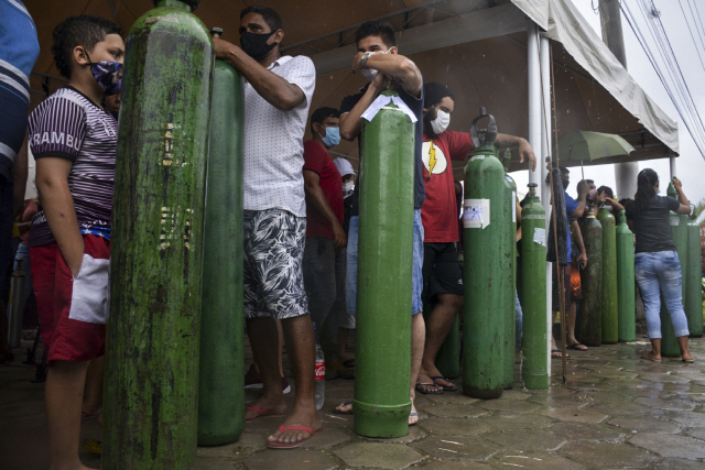 19일(현지 시간) 브라질 북부 마나우스의 가스 회사 ‘칼복시’ 앞에 코로나19 감염자 가족들이 산소를 충전하기 위해 빈 산소 탱크를 들고 줄지어 서 있다. 최근 브라질 일부 지역에서 코로나19 감염자가 급증해 중환자실이 가득 차자 코로나19 환자 14명이 산소 부족으로 숨졌다.    /AFP연합뉴스