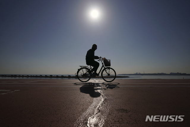 [도쿄=AP/뉴시스]21일 일본 도쿄에서 코로나19 예방을 위해 마스크를 쓴 한 남성이 자전거를 타고 지나가고 있다. 2021.01.21