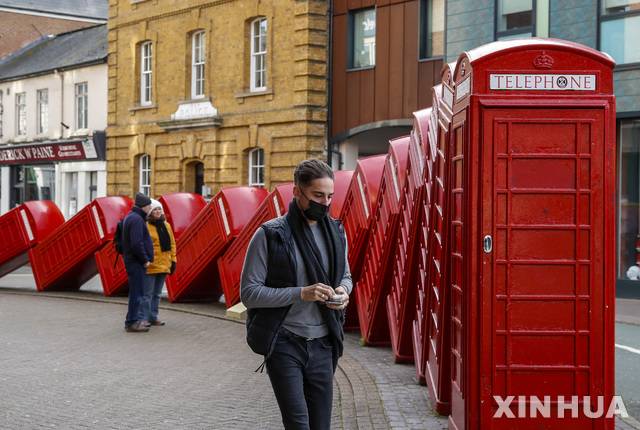 [킹스턴=신화/뉴시스]21일(현지시간) 영국 런던 근교 킹스턴에서 마스크를 쓴 한 남성이 '고장'이라는 제목의 빨간색 전화박스 조각 작품 옆을 걷고 있다. 영국에서 코로나19 신규 사망자가 1820명으로 보고돼 코로나19가 발병한 이래 하루 최다 사망자를 낸 것으로 나타났다. 2021.01.22.