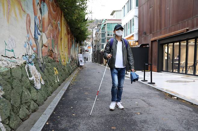 윤가브리엘 ‘HIV/AIDS 인권연대 나누리+’ 대표가 지난해 11월19일 서울 종로구 대학로에서 <한겨레>와 인터뷰를 마친 뒤 귀가하기 위해 시각장애인용 지팡이에 의지한 채 골목길을 걸어가고 있다. 윤 대표는 다국적 제약회사 로슈가 약값을 올려받기 위해 새로운 치료제인 ‘푸제온’ 공급을 거부하는 바람에 2006년에 시력의 대부분과 청력의 상당 부분을 잃었다. 장철규 선임기자 chang21@hani.co.kr
