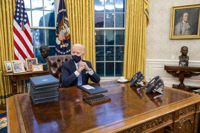 조 바이든 미국 대통령이 20일 새로 단장한 백악관 대통령 집무실에 앉아 행정명령에 서명할 준비를 하는 모습. 워싱턴=UPI 연합뉴스