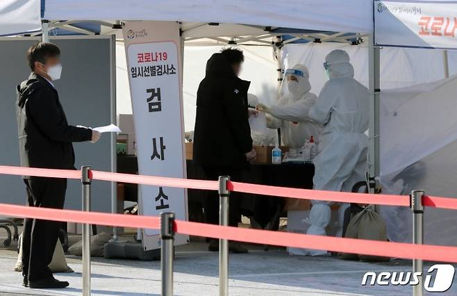 (김포공항=뉴스1) 정진욱 기자 = 국내 신종 코로나바이러스 감염증(코로나19) 확진자가 처음 발생한 지 1년째 되는 날인 20일 서울 강서구 김포공항 국내선 주차장에 마련된 임시선별진료소에서 시민들이 검체 검사를 받고 있다.2021.1.20/뉴스1  <저작권자 ⓒ 뉴스1코리아, 무단전재 및 재배포 금지>