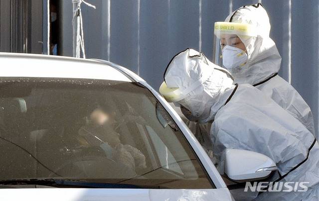 [대구=뉴시스] 이무열 기자 = 국내 신종 코로나바이러스 감염증(코로나19) 첫 확진자 발생 1년을 하루 앞둔 19일 오후 대구 수성구 대구스타디움 제3주차장에 마련된 드라이브스루 코로나19 임시선별검사소에서 의료진이 검체 채취를 하고 있다. 2021.01.19. lmy@newsis.com