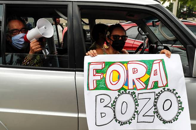 23일(현지시간) 브라질 상파울루에서 열린 자이르 보우소나루 브라질 대통령 탄핵 촉구 시위에 참가한 브라질인이 “보우소나루 나가라”는 팻말을 들고 있다. 상파울루=EPA연합뉴스