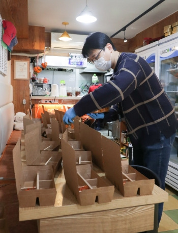 노숙인 도시락을 홀로 싸는 진달래 식당 사장님을 위해 나선 기자. 포장을 잘하려 심혈을 기울이고 있다./사진=조선일보 고운호 기자, 또 감사합니다