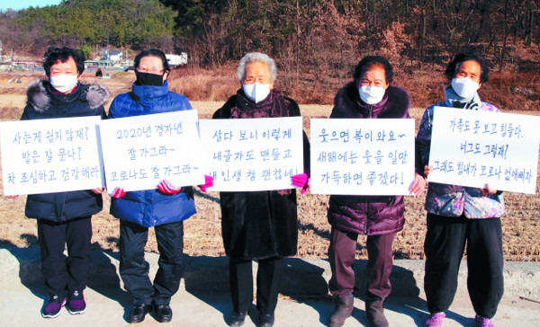 할머니들의 글씨체로 만들어진 폰트로 쓴 팻말을 들고 있다. 칠곡군 제공