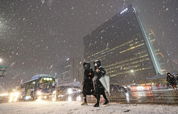 서울 전역에 대설주의보가 발효된 3일 오후 서울 광화문 광장에서 시민들이 눈을 맞으며 걸어가고 있다./연합뉴스