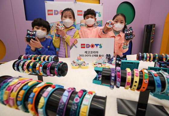 Kids pose with bracelets and ornaments made with Lego at the launching event of Lego Korea’s new do-it-yourself Lego Dots range at a pop-up store at Coex in Samseong-dong, southern Seoul on Thursday. [YONHAP]