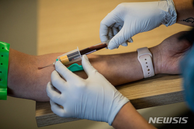 A paramedic, right, takes a blood sample from a front line ambulance worker during an antibody testing program at the Hollymore Ambulance Hub, in Birmingham, England, on Friday, June 5, 2020.  Making antibody tests widely available may help Britain lift its lockdown restrictions, because they show who has already had the COVID-19 and might have a degree of immunity from coronavirus.  (Simon Dawson/Pool via AP)