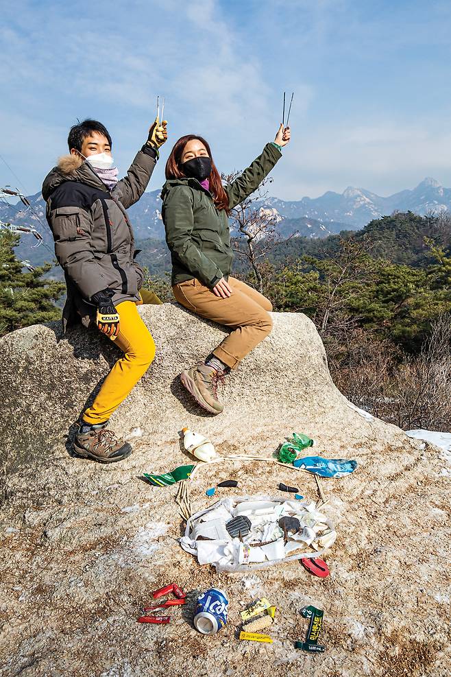 북한산 능선을 배경으로 만든 정크아트 <쓰레기 버리지 마‘소’>와 정지훈, 김강은씨.