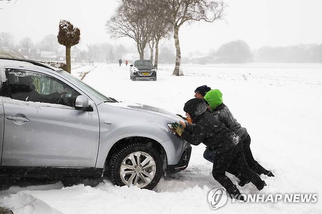 7일(현지시간) 네덜란드에서 사람들이 눈에 빠진 차를 밀고 있다. [EPA=연합뉴스]