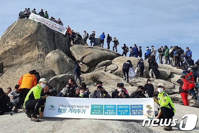 설 명절 연휴 첫날인 11일 북한산 백운대에서 국립공원 직원들과 산악안전봉사단원들이 신종 코로나바이러스 감염증(코로나19) 확산 방지를 위한 거리두기 캠페인을 하고 있다.(북한산국립공원 산악안전봉사단 제공) 2021.2.11/뉴스1 © News1 민경석 기자