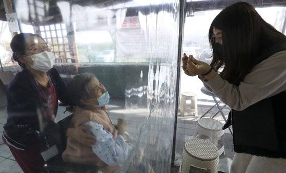 설날인 12일 오후 울산시 울주군 이손요양병원에 설치된 비닐 면회실에서 며느리가 비닐막 너머 앉은 시어머니에게 손하트를 만들어 보이고 있다. 뉴스1