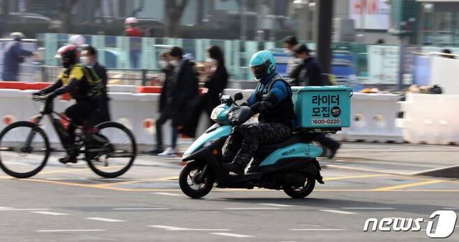 (서울=뉴스1) 황기선 기자 = 서울 광화문 사거리에서 음식배달대행 종사자가 도로를 주행하고 있다.