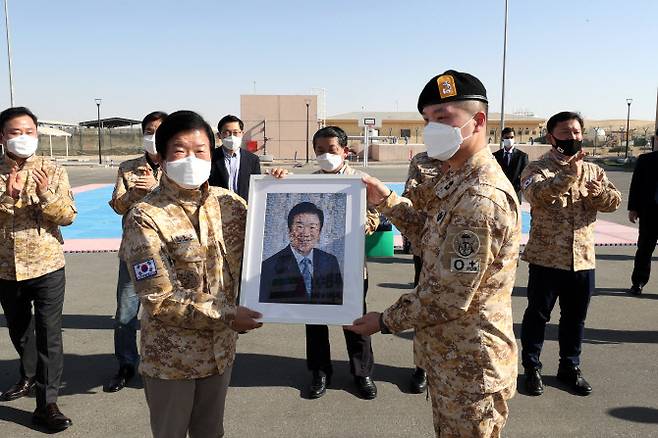 아랍에미리트(UAE)를  공식 방문하고 있는 박병석 국회의장이 설날인 12일 오후(현지시각) 아부다비 인근 UAE 군사훈련협력단(아크 부대)을 방문, 장병들을 격려한 뒤 박 의장의 얼굴을 부대 훈련사진으로 모자이크한 사진을 전달받고 있다. (사진=국회의장실 제공)