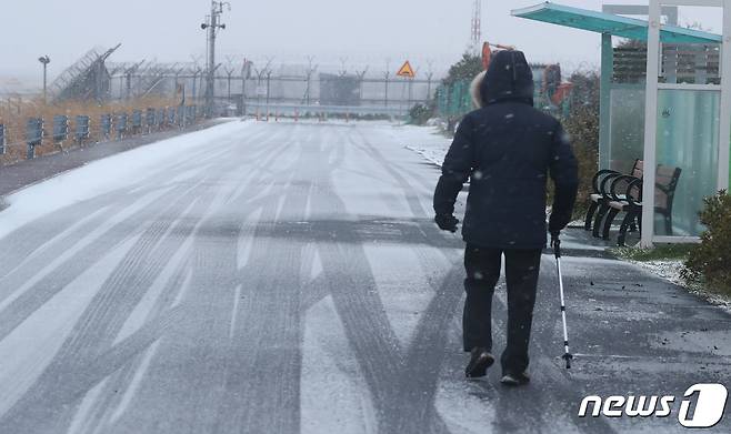 대설주의보가 발효된 18일 오전 제주시 용담동에서 한 시민이 등산용 스틱에 의지하며 걷고 있다.2021.2.18/뉴스1 © News1 오현지 기자