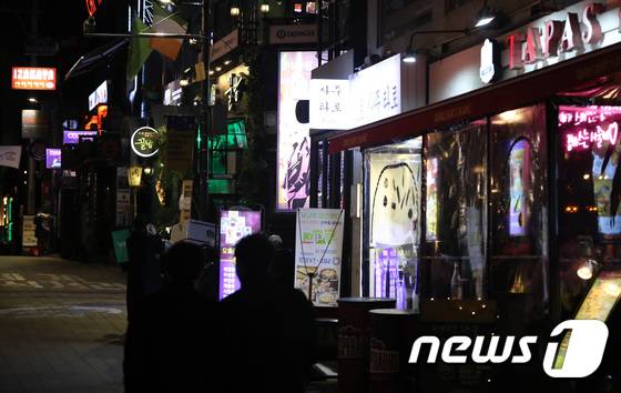 수도권의 사회적 거리두기가 2단계로 완화된 15일 저녁 서울 용산구 이태원 거리에 불 켜진 간판 사이로 시민들이 지나가고 있다. /사진 = 뉴스 1