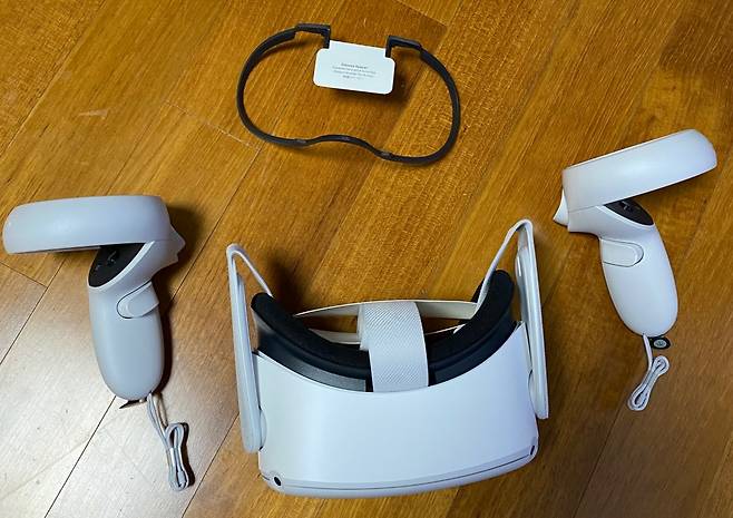 오큘러스 퀘스트2 컨트롤러 2개와 헤드셋. 위엔 안경을 쓰는 사람을 위한 보조도구가 있다.