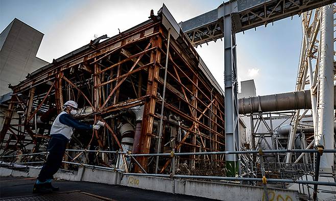 일본 도쿄전력 직원이 지난 21일 후쿠시마현의 제1 원전의 원자로 격납용기 옆에서 방사능 농도를 측정하고 있다. 오쿠마=AFP연합뉴스