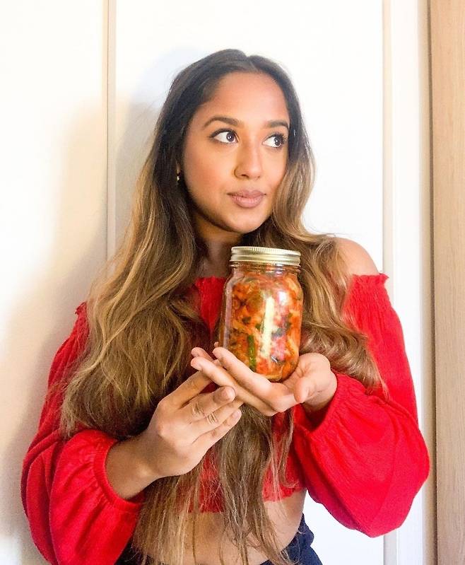 Priti Majumdar, who is Bengali and Canadian, poses while holding a jar of kimchi she made at home. (Priti Majumdar’s Instagram)