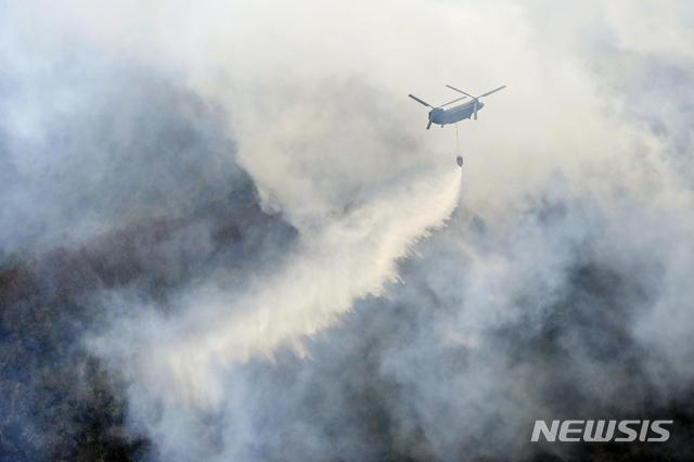 [도치기=AP/뉴시스] 일본 도치기현 아시카가시에서 산불이 발생해 24일 헬리콥터가 상공에서 물을 투하하고 있다. 지난 21일 발생한 산불은 25일까지 계속되고 있다. 2021.02.25.
