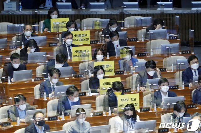 정의당 의원들이 26일 서울 여의도 국회에서 열린 본회의에서 가덕도 관련 법안을 비판하는 피켓을 의석에 붙여 놓고 있다. 2021.2.26/뉴스1 © News1