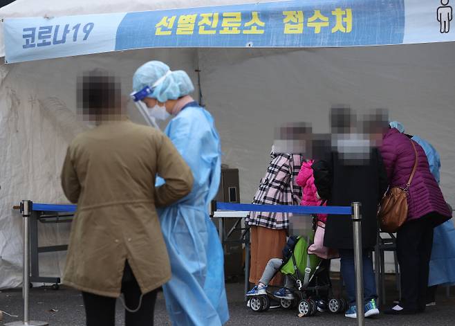 21일 오후 서울 양천구보건소에 마련된 선별진료소에서 한 가족이 검사를 받기 위해 문진표를 작성하고 있다. 연합뉴스