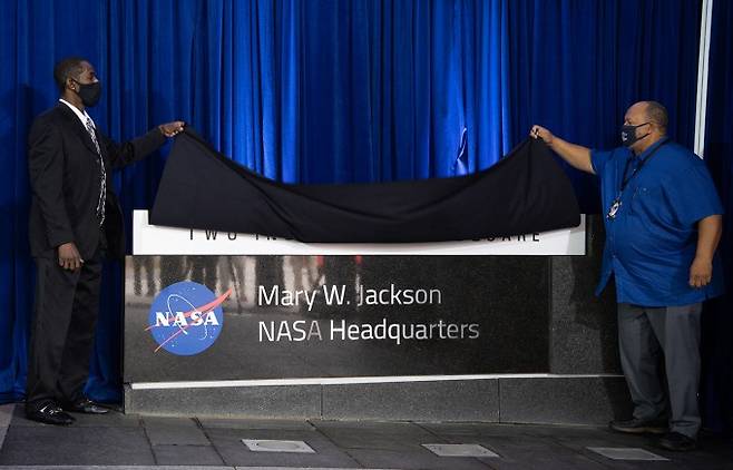 26일 미국항공우주국(NASA) 워싱턴DC 본부에서 흑인 여성 과학자 메리 잭슨을 기념하기 위해 본부명을 '메리 W. 잭슨 본부'로 명명하는 기념식이 열리고 있다. 메리 잭슨의 손자인 브라이언 잭슨(왼쪽)과 사위인 레이먼드 루이스(오른쪽)이 현판을 공개하고 있다. NASA 제공