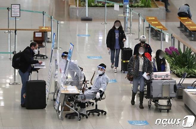 지난 23일 인천국제공항 제1터미널 입국장에서 해외입국자들이 방역관계자들로부터 안내를 받고 있다./사진제공=뉴스1